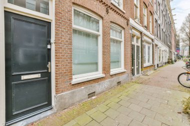 Ağaçlar ve fenerlerle dolu boş bir kaldırım sokağından tuğla evler manzarası