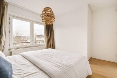 Parlak yatak odası, beyaz battaniyeli ve mavi yastıklı.