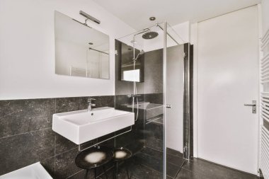 Modern banyo, siyah beyaz fayanslı duvarlar.