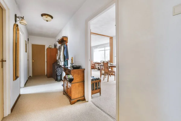 Hallway with wooden entrance door and shelves near it