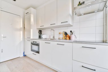 Minimalist tarzı beyaz mobilyalı, lavabolu ve sobalı hafif ev mutfağı.