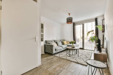 Rahat bir kanepe ve koltuğu modern dairede, rahat bir oturma odasının penceresinin yanındaki yumuşak halıya yerleştirilmiş.