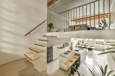 Ahşap merdiveni ve pencereli yemek odasına girişi olan ferah, parlak bir koridor.