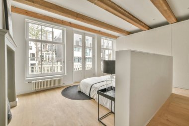 Şık komodinleri, halısı ve parke döşemesi olan ferah, parlak bir yatak odası.