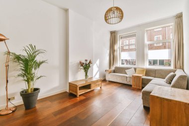 Oturma odasının rahat iç tasarımı. Pencerelerin altındaki duvara dayalı rahat bir köşe kanepesi var.