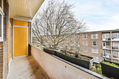 Eski tuğla binaların panoramik manzarası. Küçük balkondan park yerleri ve ağaçlar.