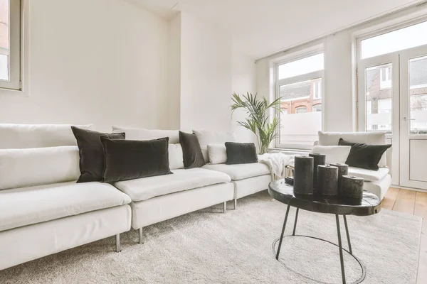 White colored sofa with white and black pillows on it in the hall