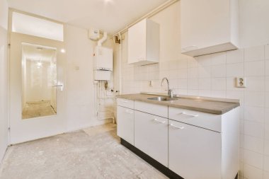 İyi organize edilmiş küçük bir ev mutfağı pencerenin altında lavabo, sobalı hafif mobilyalar ve kentsel apartmanda buzdolabı var.