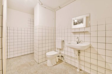 Modern sifon tuvaleti ve seramik lavabo aynanın yanındaki beyaz fayanslı duvarlara ve evdeki küçük tuvaletteki havluya monte edildi.