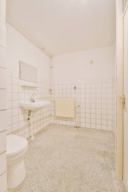 Modern sifon tuvaleti ve seramik lavabo aynanın yanındaki beyaz fayanslı duvarlara ve evdeki küçük tuvaletteki havluya monte edildi.