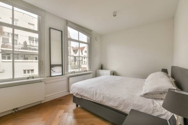 Minimalist komodinli geniş, parlak bir yatak odası ve geniş bir panoramik pencere.