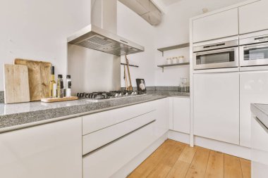 Stüdyo dairesinin modern minimalist tarzı iç tasarımı açık beyaz mutfak ve yemek masası ve sandalyeleri tavan arası lambasıyla aydınlatılmış.