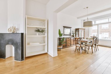 Stüdyo dairesinin modern minimalist tarzı iç tasarımı açık beyaz mutfak ve yemek masası ve sandalyeleri tavan arası lambasıyla aydınlatılmış.