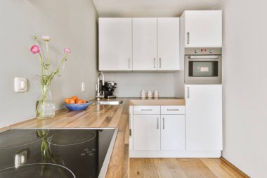 Modern ev mutfağı iç tasarımı beyaz dolaplar, dolaplar ve çelik kapüşon ile çağdaş apartmanda.