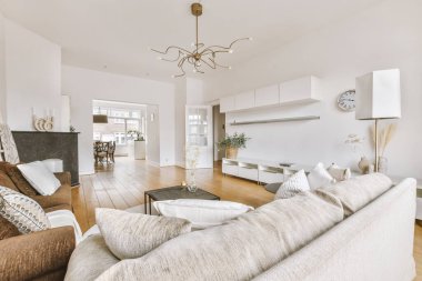 Yumuşak yastıklı rahat bir kanepe şık bir avizenin altında kemerli, ferah bir oturma odasında.