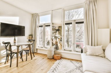 TV 'nin yanındaki koltuklar ve masa, çağdaş apartmandaki geniş odalı yemek alanına karşıdır.