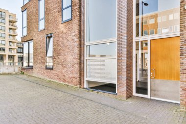 Siyah çerçeveli, ahşap kapılı, daireye açılan tuğladan bir binanın ön manzarası.