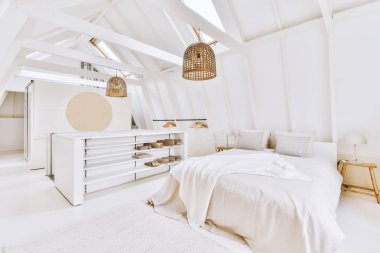 Çağdaş yatak odasının tavan arasında beyaz duvarlar var.