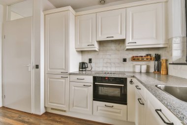 Minimalist tarzı beyaz mobilyalı, lavabolu ve sobalı bir ev mutfağı.