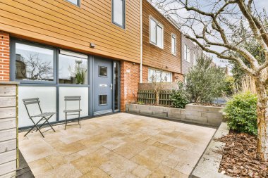 Arabaları, ağaçları ve fenerleri olan boş bir kaldırımdan panorama manzaralı evler.