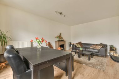 Siyah renkli yemek masası, sandalyeler ve şık bir oturma odasında yastıklı kanepe.