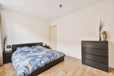 Mavi battaniyeli çift kişilik yatak ve parlak yatak odasında yastıklar.