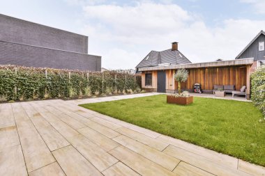 Neat paved patio with sitting area and small garden near wooden fence
