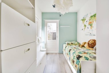 Küçük yatak odasının minimalist iç tasarımı. Köşesinde yumuşak yatak, ahşap gardırop ve lamba aydınlatmalı raflar var.