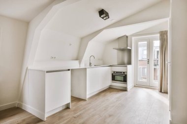 Çatısı kirişli açık mutfağı olan geniş bir çatı katı.