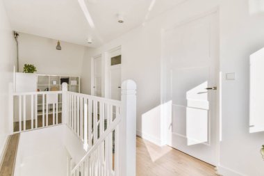 Odanın kapalı beyaz kapısı evdeki merdivenlerin üstündeki dolabın yanında.