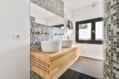 Lavabonun altında ve aynalı ahşap dolabı olan modern beyaz banyonun bir parçası.