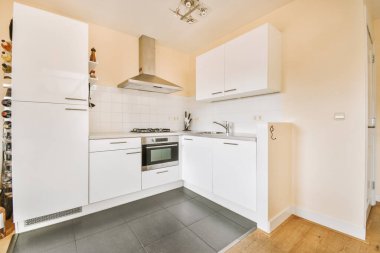 Çağdaş dairenin geniş odasındaki dinlenme odası ve mutfağın yakınındaki sandalyeli ve çiçekli masa.