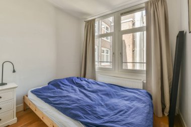 Yatak odasının iç tasarımı, yatak odası ve ahşap gardırop modern dairenin penceresinin kenarına yerleştirilmiş.