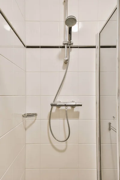 白いタイルの壁と小さな光のバスルームでシンクとトイレの近くの隅に配置されたガラスシャワー付きのバスタブ — ストック写真