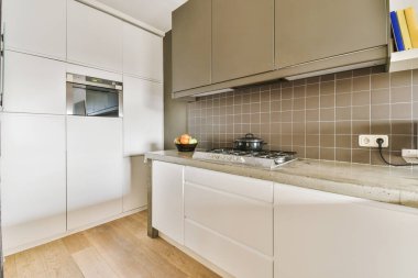 Minimalist tarzı beyaz mobilyalı, lavabolu ve sobalı bir ev mutfağı.