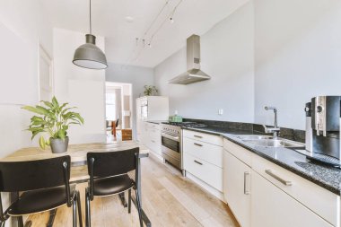 Beyaz mobilyalar ve aletlerle çatı katı tarzı bir dairede modern ev mutfağı iç tasarımı.