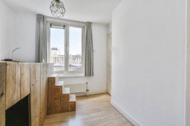 Oyun alanının yanında pencereli ve gri perdeli bir oda.