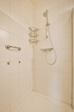 Duş muslukları cam bölmenin yanındaki fayanslı duvara bağlı ve evdeki tuvaletteki süs pervazı.