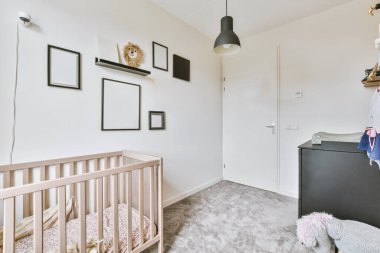 Bebek beşiği ve pencerenin yanındaki koltuğu olan beyaz odanın içi. Gün ışığında mavi çekmecelerle dolu.