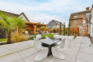 Neat paved patio with sitting area and small garden near wooden fence