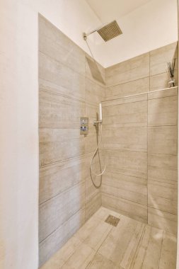 Duş musluğu modern dairede hafif tuvaletin fayanslı duvarında asılı.
