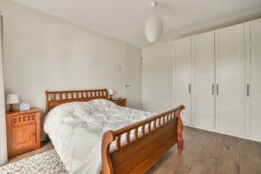 Geniş, parlak bir yatak odası, minimalist bir komodin, ayna ve geniş bir panoramik pencere.