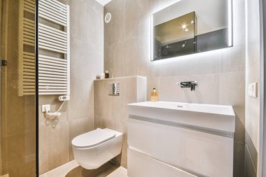 Modern sifon tuvaleti ve seramik lavabo aynanın yanındaki beyaz fayanslı duvarlara ve evdeki küçük tuvaletteki havluya monte edildi.
