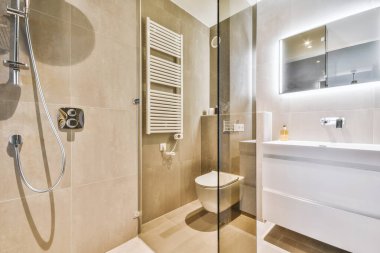 Modern sifon tuvaleti ve seramik lavabo aynanın yanındaki beyaz fayanslı duvarlara ve evdeki küçük tuvaletteki havluya monte edildi.