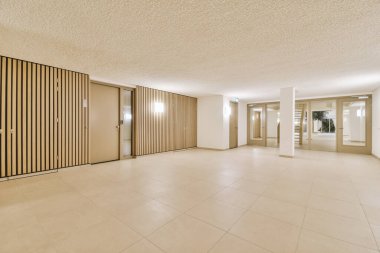 Işık koridoru, giriş kapısı olan iki katlı bir apartman dairesi. Minimalist ahşap merdivenler, gün ışığında üst kata çıkıyor.