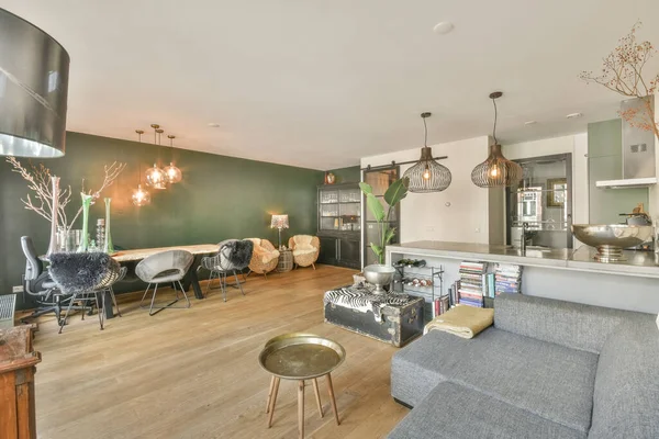 Interior of spacious light dining room and elegant chandelier located near kitchen with modern furniture and appliances