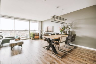Günümüz minimalist tasarımı. Hafif stüdyo dairesinin ahşap masası ve oturma odası ile beyaz duvarları ve parke zemini arasında yemek masası ve sandalyeleri var.