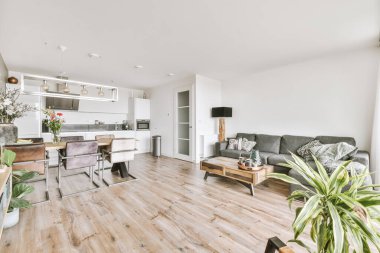 Günümüz minimalist tasarımı. Hafif stüdyo dairesinin ahşap masası ve oturma odası ile beyaz duvarları ve parke zemini arasında yemek masası ve sandalyeleri var.