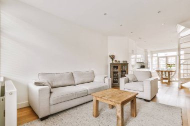 TV 'nin yanındaki koltuklar ve masa, çağdaş apartmandaki geniş odalı yemek alanına karşıdır.