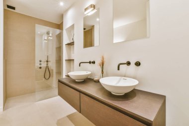 Evdeki çağdaş tuvaletteki aynanın altındaki duvarda musluk ve sıvı sabun asılı.